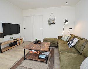 Gezellige zithoek in Bungalowpark 't Luwe Land - Bungalow 13c, De Dennen, Texel, met moderne inrichting en flatscreen-tv.