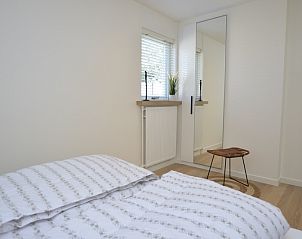 Lichte slaapkamer in Bungalowpark 't Luwe Land - Bungalow 13c, De Dennen, Texel, met spiegel en moderne inrichting.