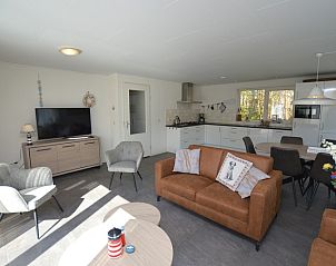 Gemtlicher Wohnbereich im Holiday home de Parel 190, Texel mit Fernseher und Sitzecke.