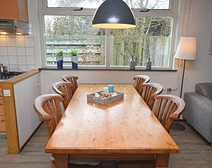 Eethoek in vakantiehuis Iris, Texel met houten tafel en uitzicht op de tuin.