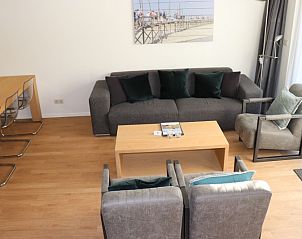 Uitzicht op de woonkamer van Vakantiehuis Gortersmient 232, Texel met comfortabele banken en open haard.