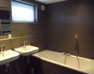 Luxe badkamer in Vakantiehuis Gortersmient 232, De Dennen, Texel met dubbele wastafel en ligbad.