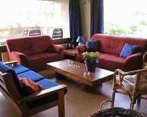 Gemtliches Wohnzimmer im Ferienhaus Waken Oog, Oost-Vlieland mit bequemen Sitzgelegenheiten und Blick auf die Natur.