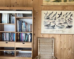 Boekenkast en stoel in Anders Wad(t) vakantiehuis op Vlieland, Waddeneilanden.