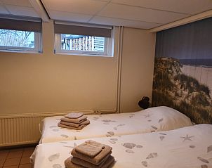 Slaapkamer in Vosseburcht vakantiehuis, Oost-Vlieland, met twee eenpersoonsbedden en strandthema decor.
