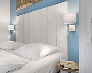 Sfeervolle slaapkamer in Vlieduyn 2-persoons appartement, Oost-Vlieland, met comfortabele bedden en leeslampjes.