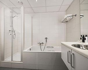 Moderne badkamer met douche en bad in WestCord Hotel de Wadden, Vlieland