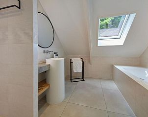 Ruime badkamer met bad en douche in WestCord Hotel de Wadden, Vlieland