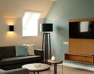 Stijlvolle zithoek in Vlierijck vakantieappartement op Vlieland met flatscreen-tv.