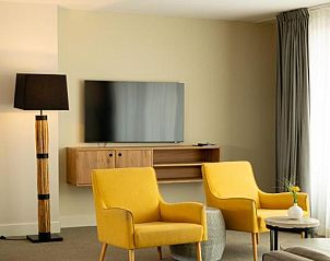 Moderne woonkamer in Vlierijck vakantieappartement op Vlieland met gele fauteuils.