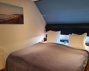 Knusse slaapkamer in Badhotel Bruin, Vlieland, met zacht beddengoed en serene sfeer.