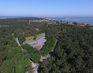 Luchtfoto van Hotel DoniaState, een vakantieappartement op Vlieland, omringd door bosrijke natuur en uitzicht op de Waddenzee.