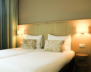 Comfortabele slaapkamer in Hotel DoniaState op Vlieland, met tweepersoonsbedden en sfeervolle verlichting voor een ontspannen verblijf.