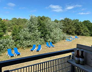 Uitzicht vanaf het balkon van Hotel DoniaState op Vlieland, met ligstoelen en een prachtig groen landschap.