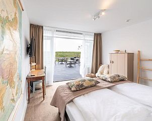 Comfortabele slaapkamer met uitzicht op het terras bij Het Vlielandhotel, Vlieland.