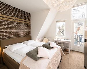 Knusse slaapkamer met bakstenen muur in Het Vlielandhotel, Vlieland, Waddeneilanden.