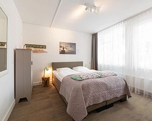 Ruime slaapkamer met grote ramen in Het Vlielandhotel, Vlieland, Waddeneilanden.