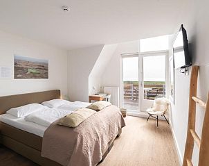 Slaapkamer met balkon en uitzicht op de natuur bij Het Vlielandhotel, Vlieland.