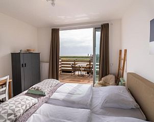 Slaapkamer met uitzicht op het terras en zee bij Het Vlielandhotel, Vlieland.
