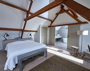 Luxe badkamer in Villa Magnolia, vakantiehuis in Oostkapelle, Walcheren, met vrijstaand bad en houten balken.