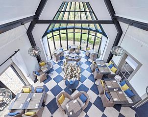 Lichte eetzaal in Villa Magnolia, vakantieappartement in Oostkapelle, Walcheren, met grote ramen en tuinzicht.