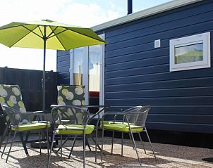 Buitenterras van Zeeschuimer chalet met parasol in Halfweg, Terschelling.