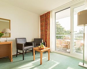 Lichte woonkamer met toegang tot balkon in Fletcher Resort-Hotel Amelander Kaap, Hollum, Ameland voor een ontspannen sfeer.