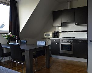 Gezellige eetruimte in Wijnberg Appartementen, Hollum, Ameland met keuken en tafel.