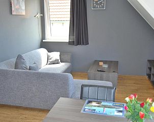 Stijlvolle woonkamer in Wijnberg Appartementen, Hollum, Ameland met grijze bank.