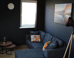 Knusse zithoek in Wijnberg Appartementen, Hollum, Ameland met moderne lamp.