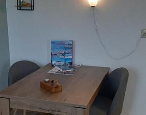 Eethoek met houten tafel en stoelen in Bij De Vuurtoren appartement, Hollum, Ameland.