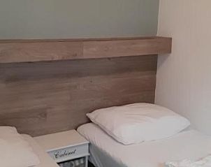 Slaapkamer met twee bedden en houten wanddecoratie in Bij De Vuurtoren appartement, Hollum, Ameland.