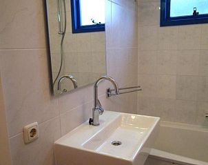 Moderne badkamer in Hollumerstrand appartement, Hollum, Ameland, met ruime wastafel en badkuip.