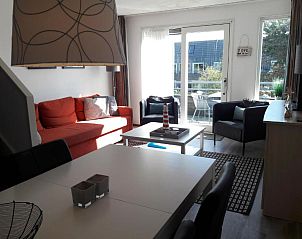 Moderne woonkamer in Hollumerstrand appartement, Hollum, Ameland, met frisse inrichting en toegang tot balkon.