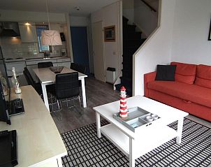 Stijlvolle woonkamer in Hollumerstrand appartement, Hollum, Ameland, met comfortabele bank en decoratieve details.