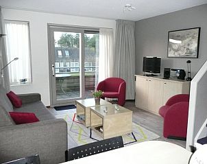 Woonkamer in Kaapshoff 32, Hollum, Ameland, met balkon en moderne meubels.