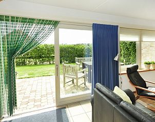 Zonnige veranda van Appartementenboerderij de Hek Oost, Hoorn, Terschelling met uitzicht op tuin.