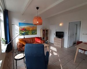 Lichte woonkamer in Aike van Rel appartement, Hoorn, Terschelling met moderne inrichting en kleurrijke kunst.