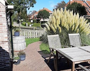Zonnig terras bij appartement Noordhoorn in Hoorn, Terschelling, omgeven door groene natuur.