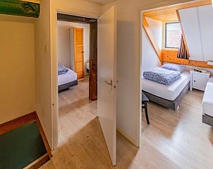Twee slaapkamers in Haas 2 appartement, Hoorn, Terschelling met comfortabele bedden en houten details.