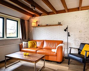 Comfortabele zithoek in appartement Kip 2, Hoorn, Terschelling met leren bank en houten accenten.