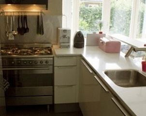 Moderne Kche im Ferienhaus Oosterkooi in Hoorn, Terschelling, mit Blick auf den grnen Garten.