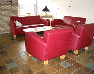 Cozy living room of De Zicht apartment on Terschelling with comfortable red couches.
