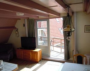 Bright living room with access to balcony in apartment Havenzicht, West, Terschelling, ideal for a relaxing vacation on the Wadden Islands.