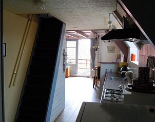 Open kitchen and dining area in apartment Havenzicht, West, Terschelling, with stairs to upper floor for a spacious feeling.