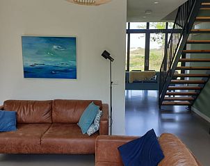 Stijlvolle woonkamer in Vakantiehuisje in Midsland-noord, Terschelling. Comfortabele zitruimte met kunst en uitzicht op de natuur.