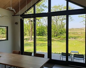 Eetkamer met uitzicht op groene omgeving in Vakantiehuisje in Midsland-noord, Terschelling. Geniet van de natuur op de Waddeneilanden.