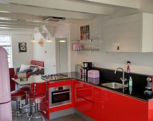 Stijlvolle keuken in vakantiehuis WadsEb.com in Klein Hoorn, Terschelling, met rode accenten en moderne apparatuur.