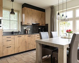 Eethoek van De Dijkwachter **** in Ballum, Ameland met houten tafel en leren stoelen voor gezellige maaltijden.