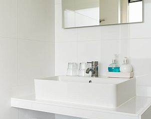 Moderne badkamer in Vakantiehuis in Ballum, Ameland, met wastafel en spiegel.